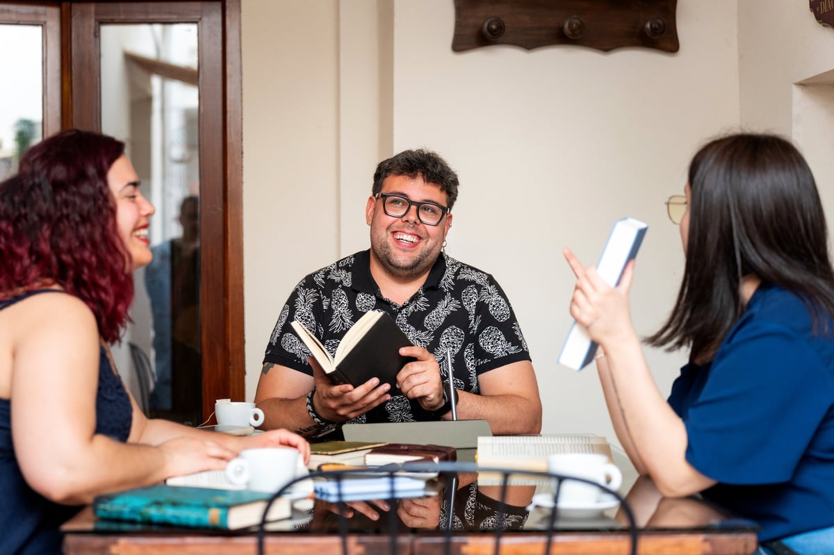 Smiling friends enjoying a book club meeting at a cafe, discussing literature and sharing their thoughts