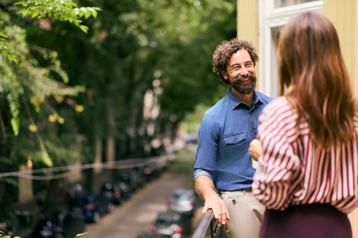 A man and a woman enjoying a lighthearted discussion on a sunny outdoor balcony