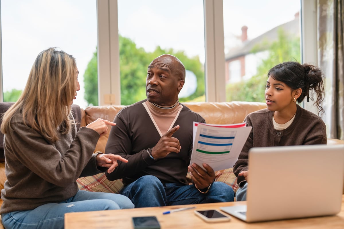 Three people engage in a lively discussion about project plans at home in the afternoon, sharing ideas and reviewing documents together