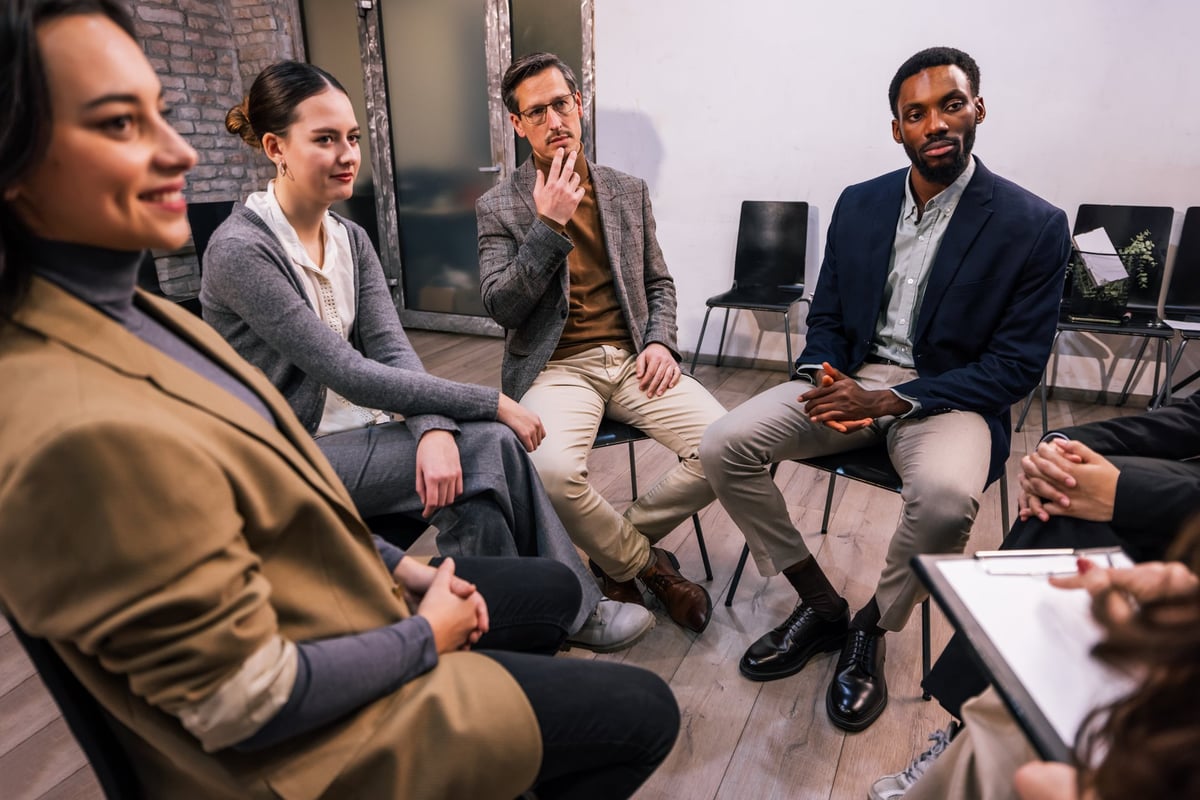 Group of people sitting in a circle during a session with a professional, showing communication and support